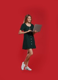 Photo of Full length portrait of young woman with modern laptop on red background