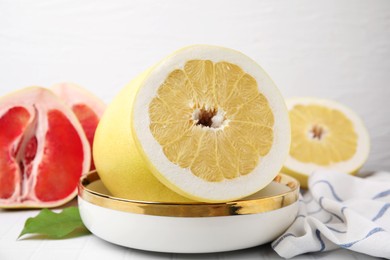 Photo of Tasty pomelo fruits on white tiled table, closeup