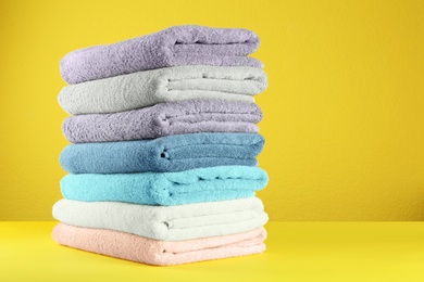 Different fresh soft terry towels on yellow background