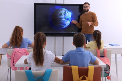 Teacher near interactive board in classroom during lesson