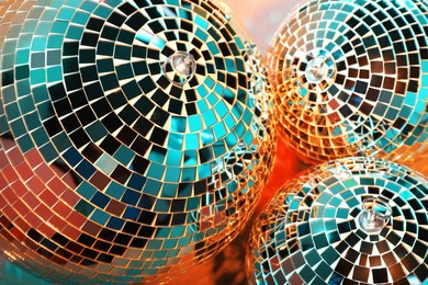 Photo of Bright shiny disco balls on color background, above view