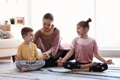 Young mother and her children practicing yoga at home
