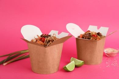 Boxes of wok noodles with seafood on pink background