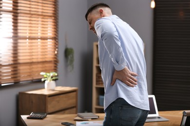 Man suffering from back pain in office. Symptom of poor posture