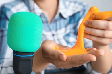 Woman making ASMR sounds with microphone and bright slime, closeup