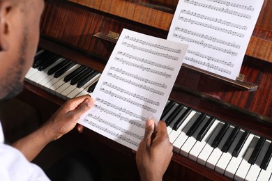 African-American man with note sheets at piano, closeup. Talented musician