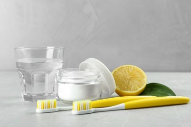 Photo of Toothbrushes, lemon and jar of baking soda on light grey table