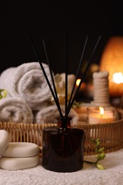 Aromatic reed air freshener, rolled towels and spa stones on table