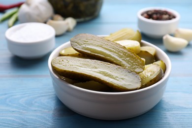 Bowl with pickled cucumbers on light blue table, closeup