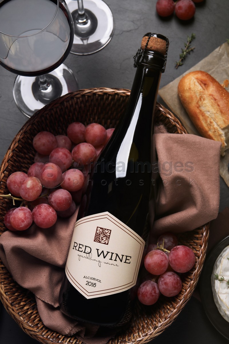 Flat lay composition with bottle of red wine and snacks on black table