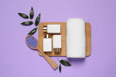 Spa layout with cosmetic and towel on violet background, flat lay