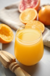 Freshly made juice, oranges and reamer on light grey table
