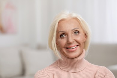Portrait of happy mature woman indoors. Space for text