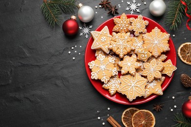 Tasty Christmas cookies and festive decor on black table, flat lay. Space for text