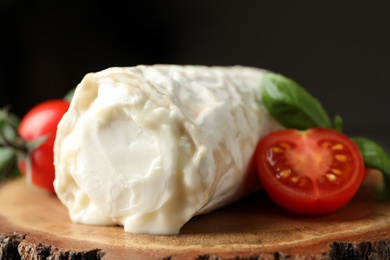 Delicious fresh goat cheese with tomatoes on wood, closeup