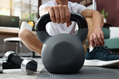 Man with kettlebell on floor at home, closeup