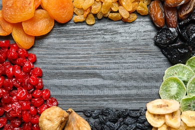 Frame made of different dried fruits on wooden background, flat lay with space for text. Healthy lifestyle