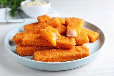 Fresh breaded fish fingers served on white table