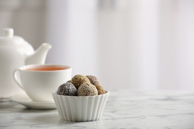 Different delicious vegan candy balls and tea on white marble table indoors. Space for text