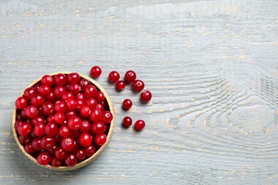 Photo of Tasty ripe cranberries on grey wooden table, flat lay. Space for text