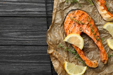 Photo of Tasty grilled salmon steak and ingredients on black wooden table, top view. Space for text