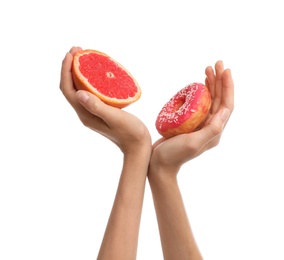 Woman choosing between doughnut and fresh grapefruit on white background, closeup
