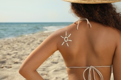 African American woman with sun protection cream on shoulder at beach, back view