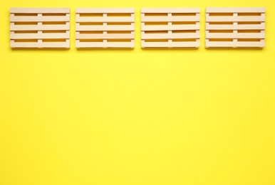 Wooden pallets on yellow background, flat lay. Space or text