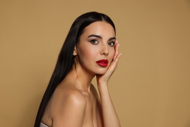 Portrait of young woman wearing beautiful red lipstick on beige background. Space for text