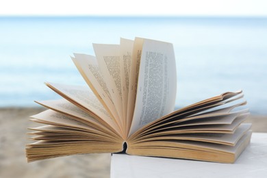 Open book on white table near sea