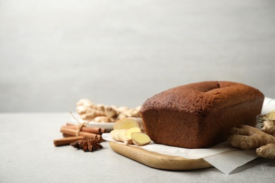 Delicious gingerbread cake and ingredients on light grey table, space for text