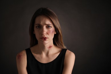 Woman with facial injuries on black background. Domestic violence victim