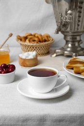 Photo of Aromatic tea, traditional Russian samovar and treats on table