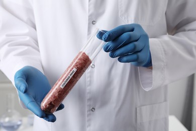 Photo of Scientist holding test tube with raw minced cultured meat in laboratory, closeup