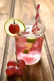 Soda water with grapes, ice and lime on wooden table. Refreshing drink