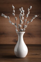 Beautiful bouquet of pussy willow branches in vase on wooden table