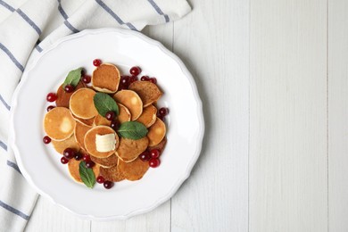 Cereal pancakes with cranberries and butter on white wooden table, flat lay. Space for text