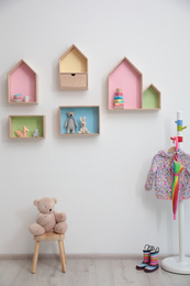 Stylish baby room interior design with house shaped shelves and coat rack