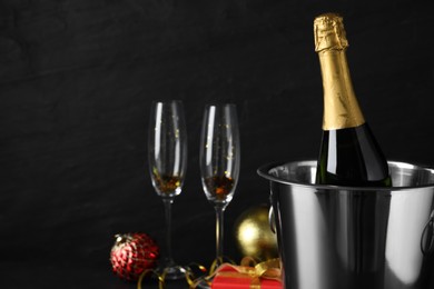 Happy New Year! Bottle of sparkling wine in bucket and glasses on black background