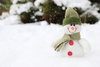 Cute small snowman toy on snow outdoors, space for text