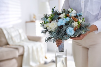 Woman putting beautiful wedding winter bouquet in vase at home, closeup. Space for text
