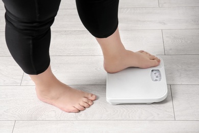 Overweight woman using scales indoors