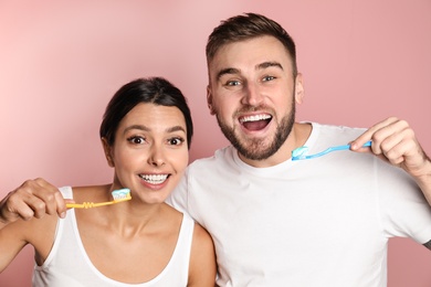 Young couple with toothbrushes and paste on color background. Teeth care