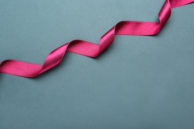 Beautiful pink ribbon on grey background, top view. Space for text