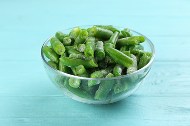 Frozen cut green beans on light blue wooden table. Vegetable preservation