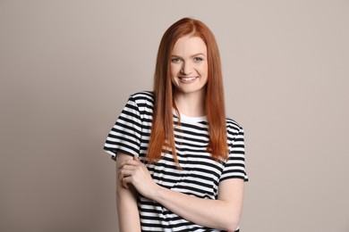 Candid portrait of happy young woman with charming smile and gorgeous red hair on beige background