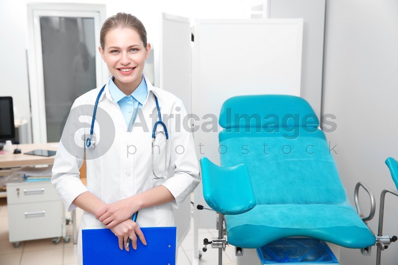 Portrait of young gynecologist with clipboard at workplace