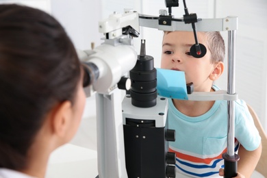 Children's doctor examining little boy with ophthalmic equipment in clinic
