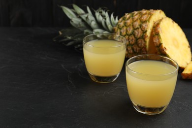Photo of Delicious fresh pineapple juice on black table. Space for text