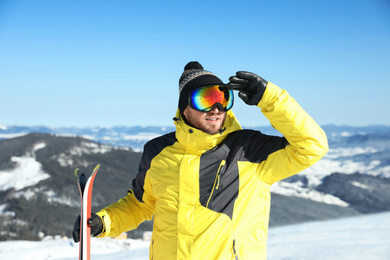 Happy man with ski equipment in mountains. Winter vacation
